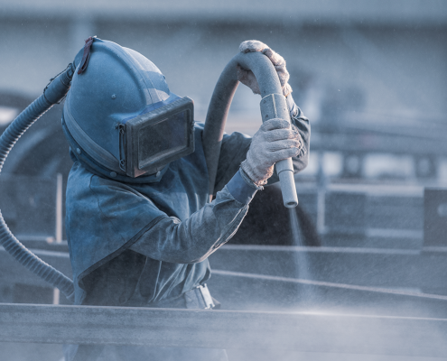 A person in PPE performing dustless blasting